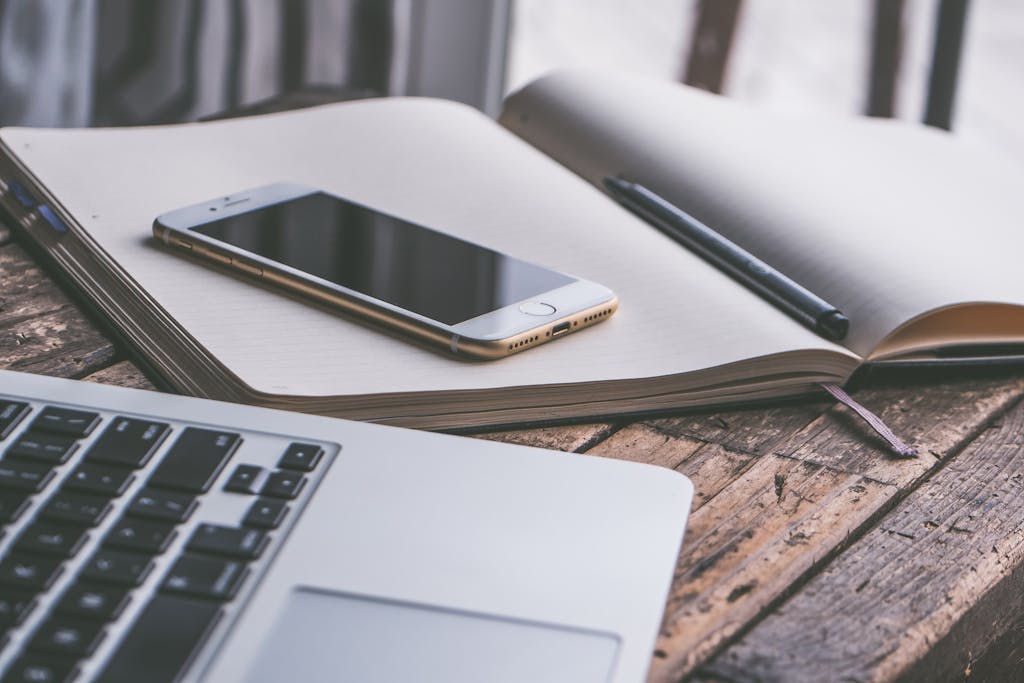 Gold Iphone 7 on Top of Book Beside Macbook