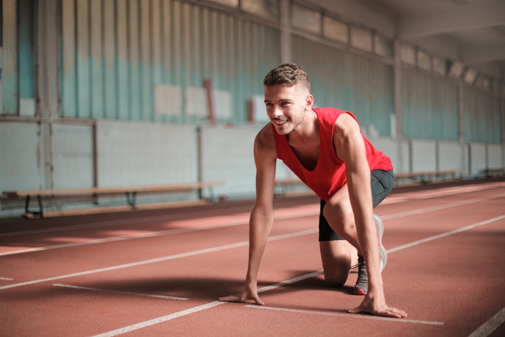 Photo of Smiling Man in Active Wear On His Marks on Running Track