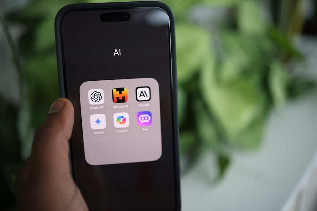 Close-up of a hand holding a smartphone with AI applications on screen.